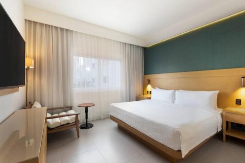 een hotelkamer met een bed en een televisie bij Courtyard by Marriott Cancun Airport in Cancun