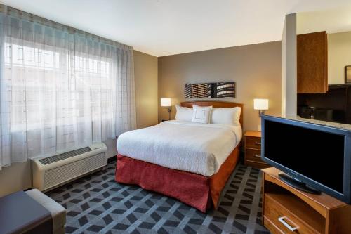a hotel room with a bed and a flat screen tv at TownePlace Suites Detroit Dearborn in Dearborn