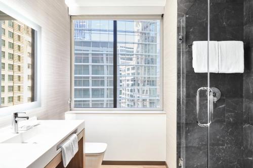 a bathroom with a shower and a toilet and a window at AC Hotel by Marriott Houston Downtown in Houston