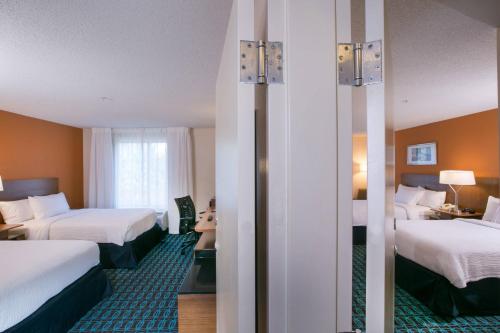 a hotel room with two beds and a mirror at Fairfield Inn & Suites by Marriott Dover in Dover