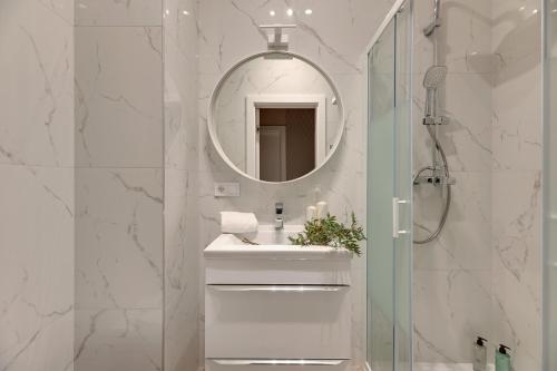 a white bathroom with a sink and a mirror at CityFlow by Welcome Apartment in Gdańsk