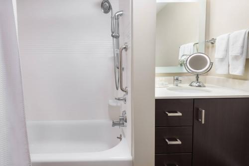 a bathroom with a shower and a sink and a mirror at TownePlace Suites by Marriott Latham Albany Airport in Latham