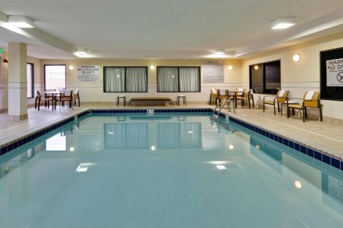 una piscina con mesas y sillas en una habitación de hotel en Courtyard Chicago Southeast/Hammond, Indiana, en Hammond