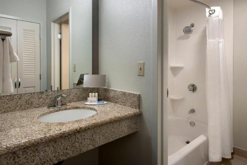 a bathroom with a sink and a mirror and a tub at Courtyard by Marriott Boston Norwood/Canton in Norwood