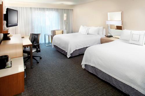 a hotel room with two beds and a desk at Courtyard by Marriott Lansing in Lansing