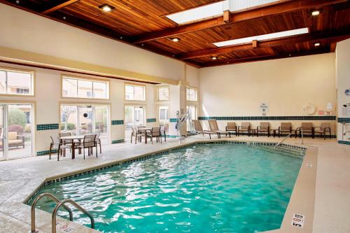 a swimming pool with tables and chairs in a building at Courtyard by Marriott Lansing in Lansing