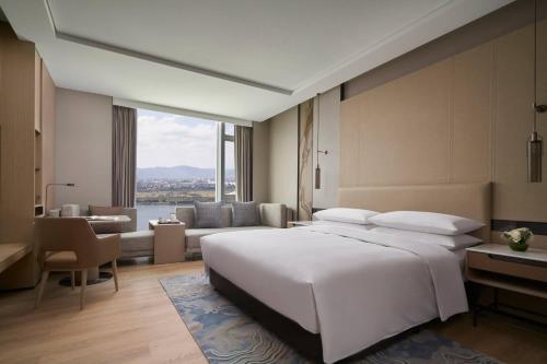 a bedroom with a large white bed and a living room at Fuzhou Marriott Hotel Riverside in Fuzhou