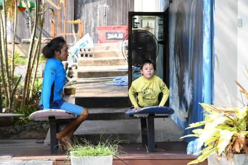 a woman and a boy sitting onools in front of some stairs at Baan Andaman Sea Surf in Patong Beach