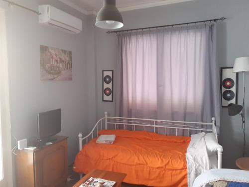 1 dormitorio con 1 cama con colcha de color naranja en ELENI's House-Near the Old Railway Station, en Nauplia