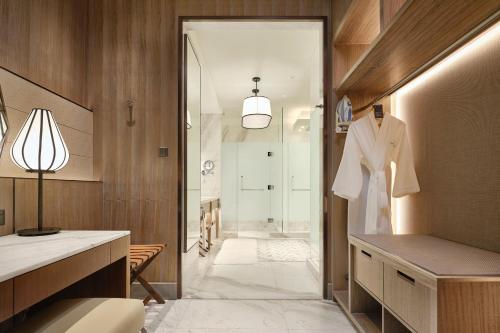 a bathroom with a walk in shower and a robe at Sheraton Saigon Grand Opera Hotel in Ho Chi Minh City