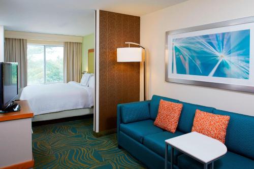 um quarto de hotel com um sofá azul e uma cama em SpringHill Suites by Marriott Atlanta Six Flags em Lithia Springs