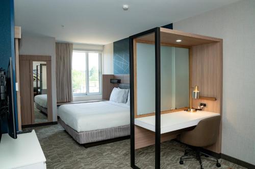 Habitación de hotel con cama y espejo en SpringHill Suites by Marriott Woodbridge, en Woodbridge