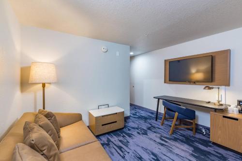 a hotel room with a couch and a desk and a television at Fairfield Inn and Suites by Marriott Tampa North in Tampa