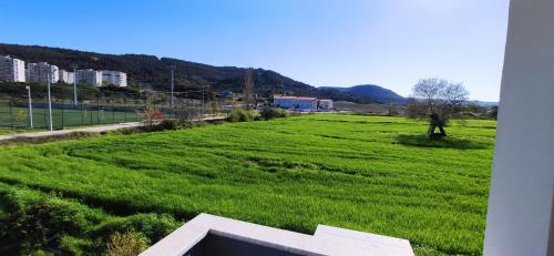 a large field of green grass with buildings in the background at Eceabat Doğa Pansiyon-Hotel in Eceabat