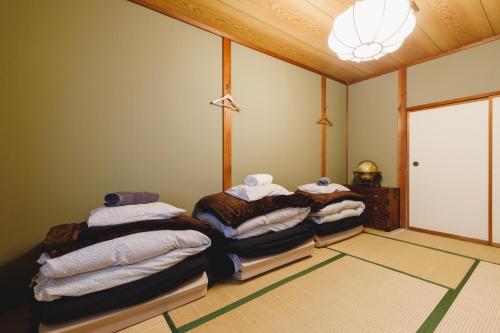 - une chambre avec 3 lits et des serviettes dans l'établissement Couch Potato Hostel - Vacation STAY 88241, à Matsumoto