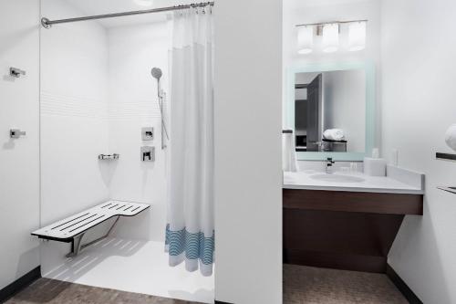 a white bathroom with a shower and a sink at TownePlace Suites by Marriott Loveland Fort Collins in Loveland