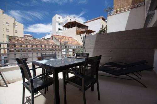 y balcón con mesa de cristal y sillas. en Malaga Andes Beach, en Málaga