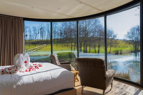 a bedroom with a bed and a view of a river at Domaine de Rymska & Spa - Relais & Châteaux in Saint-Jean-de-Trézy