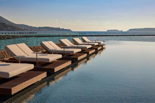 a row of chaise lounges on a dock in the water at W Costa Navarino in Pylos