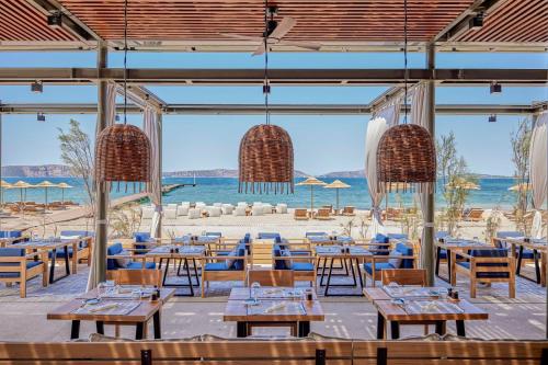 a restaurant on the beach with tables and chairs at W Costa Navarino in Pylos