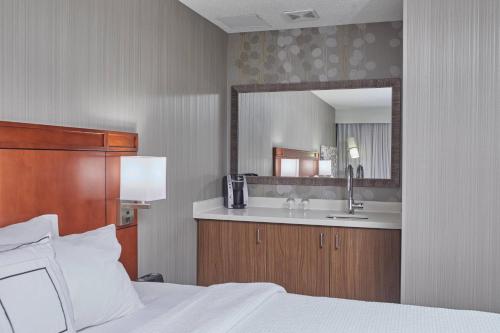 a bedroom with a bed and a sink and a mirror at Courtyard by Marriott Eugene Springfield in Springfield