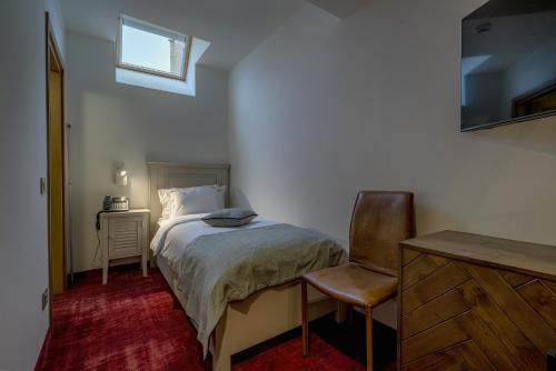 a bedroom with a bed and a chair and a window at La Boheme Boutique Casa Soare in Bucharest