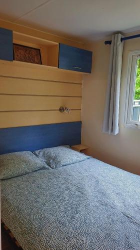 - une chambre avec un lit doté d'une tête de lit bleue et d'une fenêtre dans l'établissement Camping Marvilla Parks -Parc des roches 91530, à Saint-Chéron