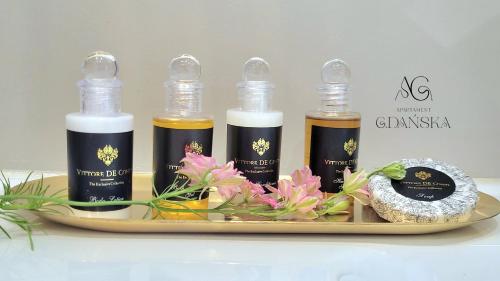 four bottles of oils on a tray with flowers at Apartament Gdańska in Gdańsk