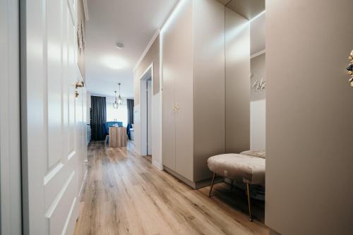 a hallway with white walls and wood floors and a bed at Apartament Talaso in Puck