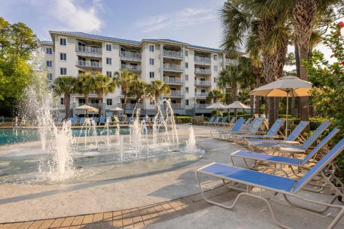 a fountain in front of a hotel with lounge chairs and a building at Marriott's SurfWatch in Hilton Head Island