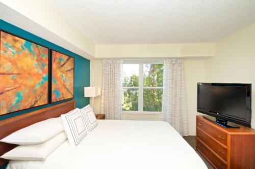 a bedroom with a bed and a tv and a window at Residence Inn by Marriott Evansville East in Evansville