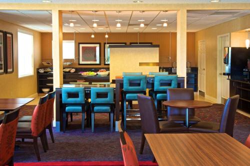 a dining room with tables and blue chairs at Residence Inn by Marriott Evansville East in Evansville