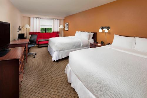 a hotel room with two beds and a red couch at Four Points by Sheraton Manhattan in Manhattan