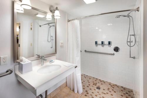 a white bathroom with a sink and a shower at Four Points by Sheraton Manhattan in Manhattan