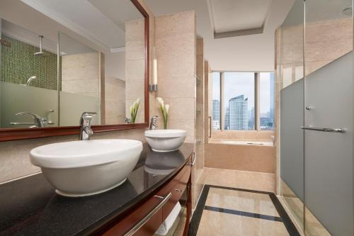 Nanning Marriott Hotel في نانينغ: حمام به مغسلتين وحوض استحمام ودش