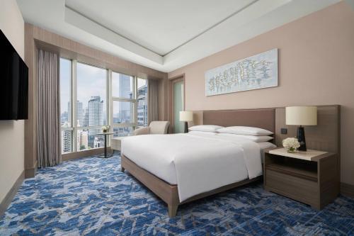 Nanning Marriott Hotel في نانينغ: غرفة نوم بسرير ابيض كبير ونوافذ كبيرة