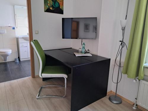 uma secretária preta com uma cadeira verde num quarto em Apartment-Hotel Schillerplatz em Wittenberge