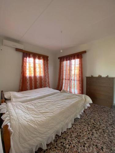 a bedroom with a large bed and two windows at Case di Stavros 2 in Pylos
