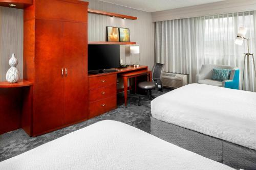 a hotel room with a bed and a desk with a television at Courtyard by Marriott San Antonio Six Flags at The RIM in San Antonio