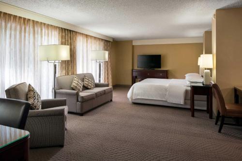 a hotel room with a bed and a couch and chair at Sheraton Palo Alto Hotel in Palo Alto