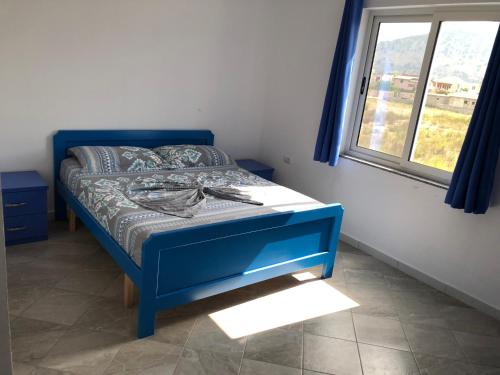 a blue bed in a room with a window at Doci Seven Hotel in Velipojë