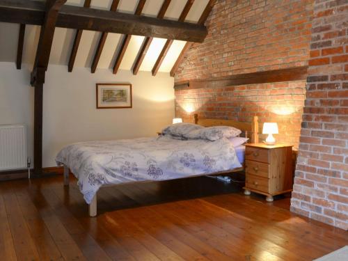 um quarto com uma cama e uma parede de tijolos em Church Farm Barn - Ukc3739 em Bawdeswell