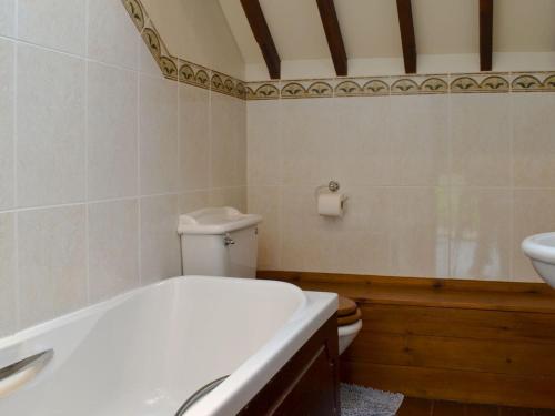 a bathroom with a tub and a toilet and a sink at Church Farm Barn - Ukc3739 in Bawdeswell