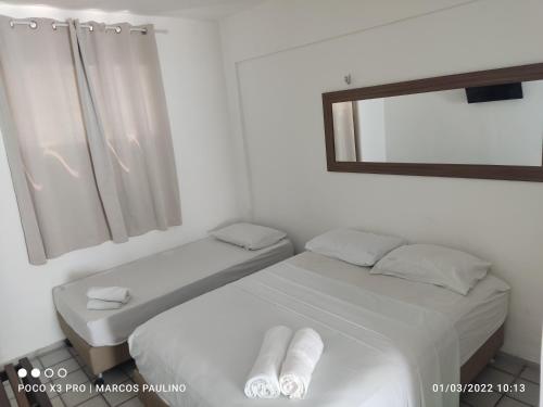 a white bedroom with two beds and a mirror at Pousada Temporada Atlântica in Fortaleza