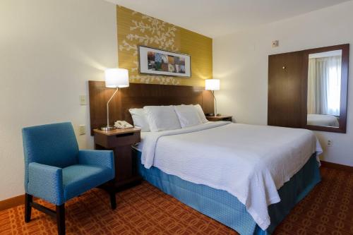 a hotel room with a bed and a blue chair at Fairfield Inn and Suites by Marriott Potomac Mills Woodbridge in Woodbridge
