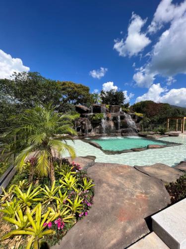 a swimming pool with a waterfall and palm trees at Pousada do Batata in Capitólio