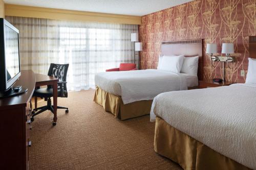 a hotel room with two beds and a desk and a television at Courtyard Costa Mesa South Coast Metro in Santa Ana