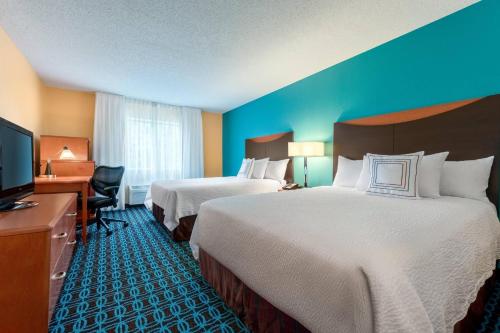 a hotel room with two beds and a flat screen tv at Fairfield Inn & Suites Stevens Point in Stevens Point