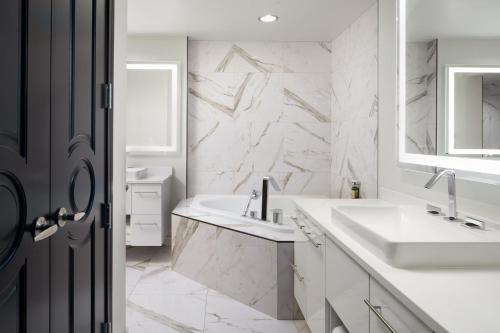 a white bathroom with two sinks and a mirror at The Davenport Grand, Autograph Collection in Spokane