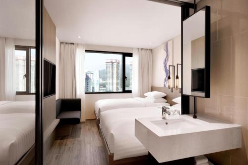 uma casa de banho com 2 camas, um lavatório e um espelho. em Fairfield by Marriott Busan em Busan